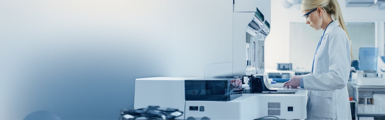 Female Research Scientist Putting Test Tubes with Blood Samples into Analyzer