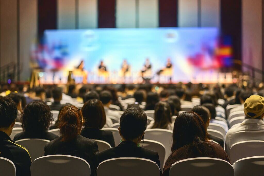 2412_Rear view of audience listening to speakers on the stagee in conference