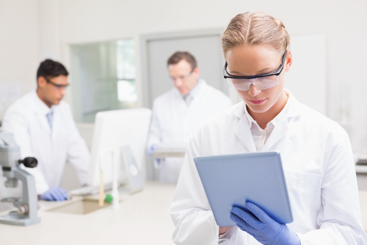 3242_Scientist using tablet while colleagues working behind